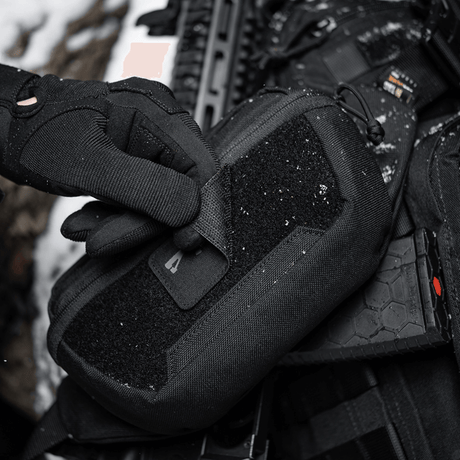 Taktisk utstyr med M-Tac AR-15 223/5,56 Laser Cut-patch i snødekt miljø.