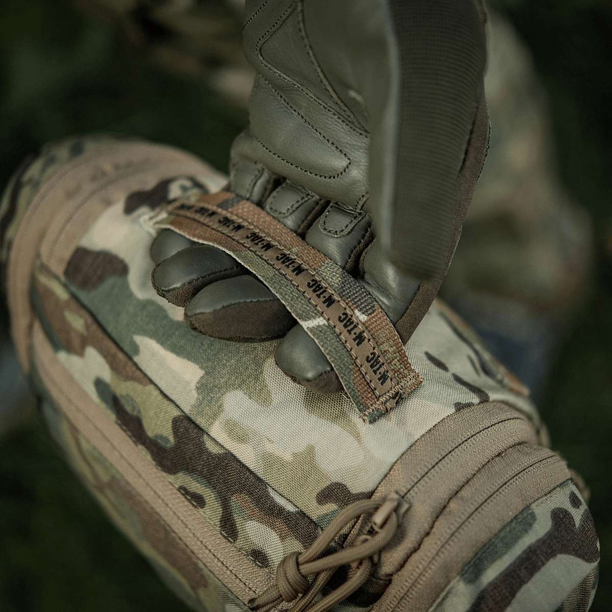 M-Tac Toilettaske Elite Gen.II i camouflage design, holdt af en hånd med taktiske handsker til udendørs brug.