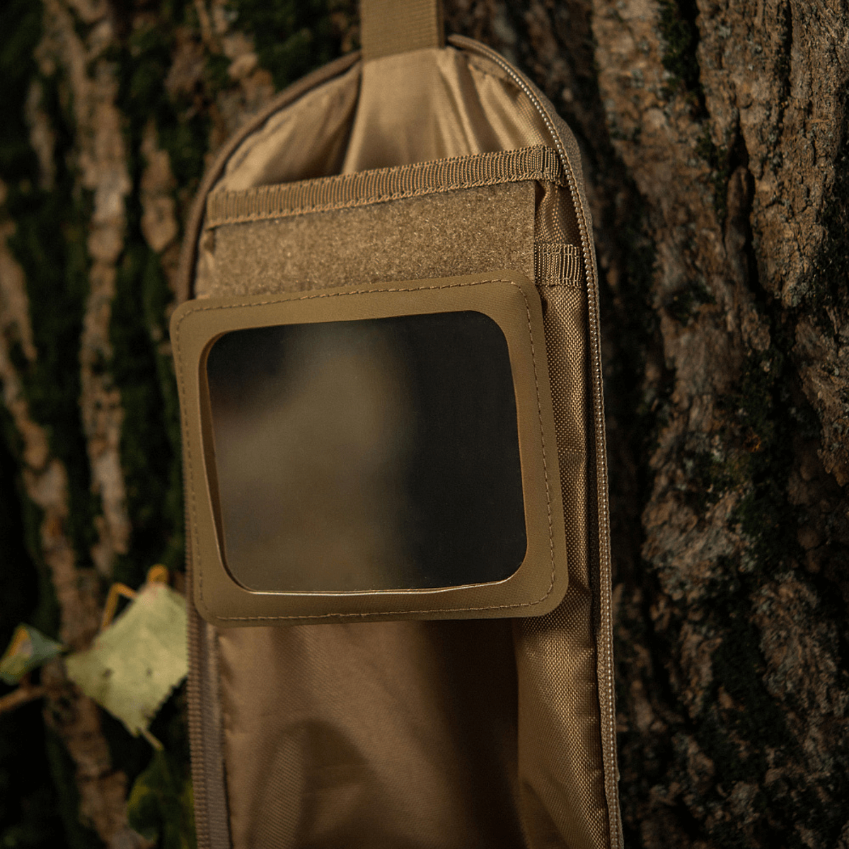 M-Tac Toilettaske Elite Gen.II hængende på et træ, ideel til opbevaring af toiletartikler under rejseeventyr.