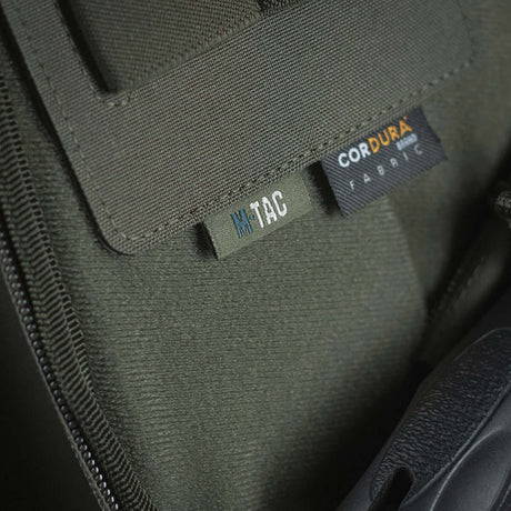 Close-up of M-Tac Double Mag Pouch Hook Backed Magazine with Cordura fabric label and Velcro attachment details in dark green.