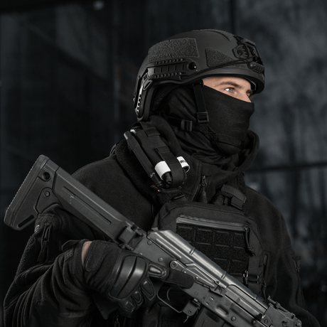 Taktisk person iført sort tøj og hjelm med våben og udstyr, klar til mission.