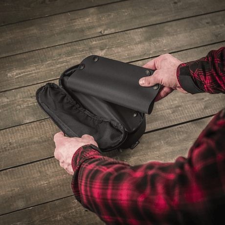 M‑Tac Field Vedligeholdelsesbakke 18x30 cm foldet ud af mand i rød skovmandsskjorte, viser sort moderne polymerkompositmateriale.