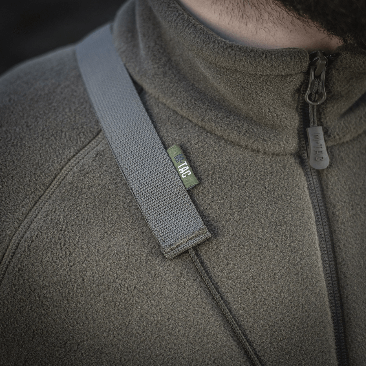 M‑Tac Pocket Bag Elite HEX bæres let på en persons jakkebryst, viser holdbar YKK lynlås og solid stropmateriale.