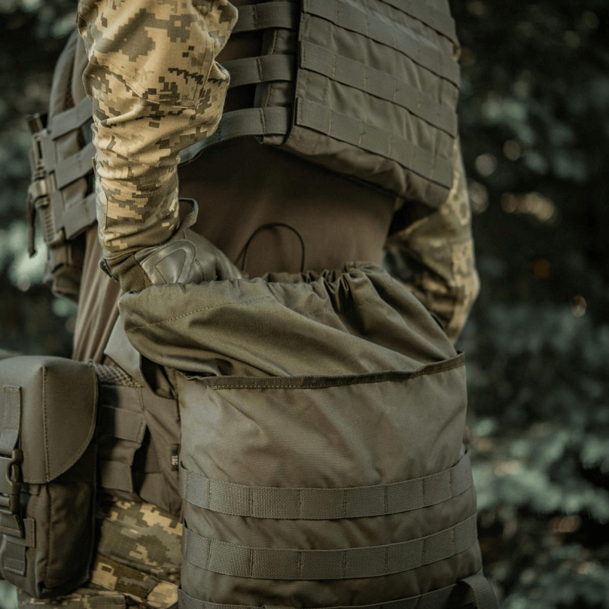 Person bærer en M-Tac Pouch Sukharka Gen.3 XL monteret på MOLLE-system, viser holdbarhed i Cordura 500D-materiale i felten.