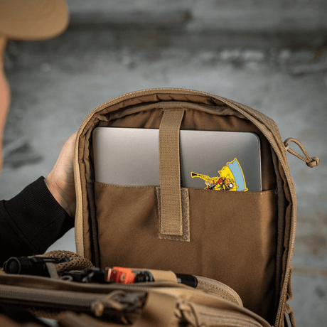 M-Tac Tablet Bag Laser Cut Hex med åbent rum, der afslører en laptop og et farverigt klistermærke indeni, viser rummelighed og design.