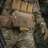 M-Tac Large Elite Gen.II Skuldertaske i brug til taktisk udstyr med Cordura 500D materiale og YKK lynlåse, set i kamouflage omgivelser.