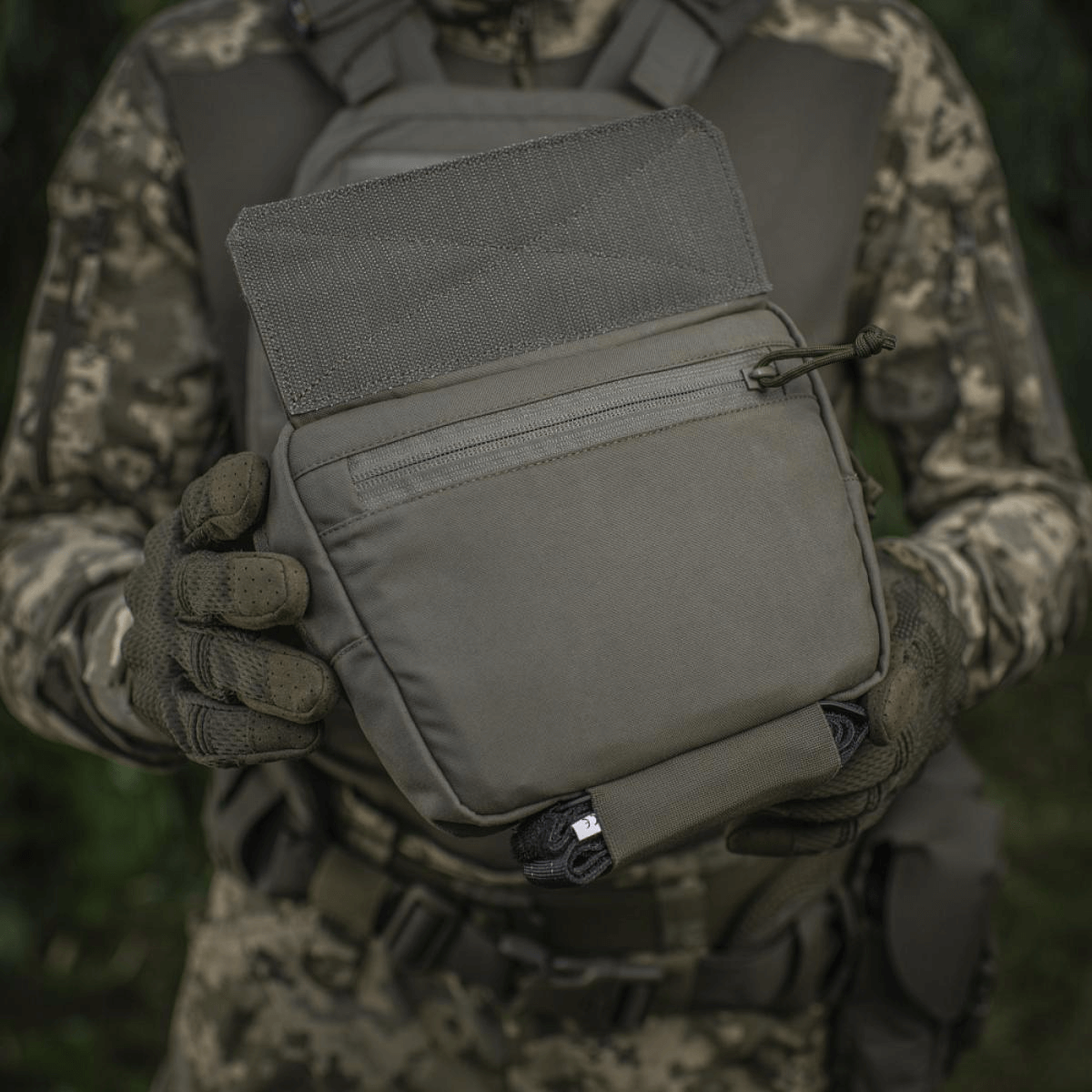 M-Tac Large Elite Gen.II Skuldertaske holdt af person i camouflage, fremstillet af Cordura 500D, perfekt til taktisk brug og udstyrstransport.