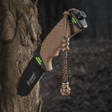 M-Tac Knife Lanyard Scandinavian Granule på en kniv, hængende fra et træ, viser et stilfuldt design og praktisk brug.