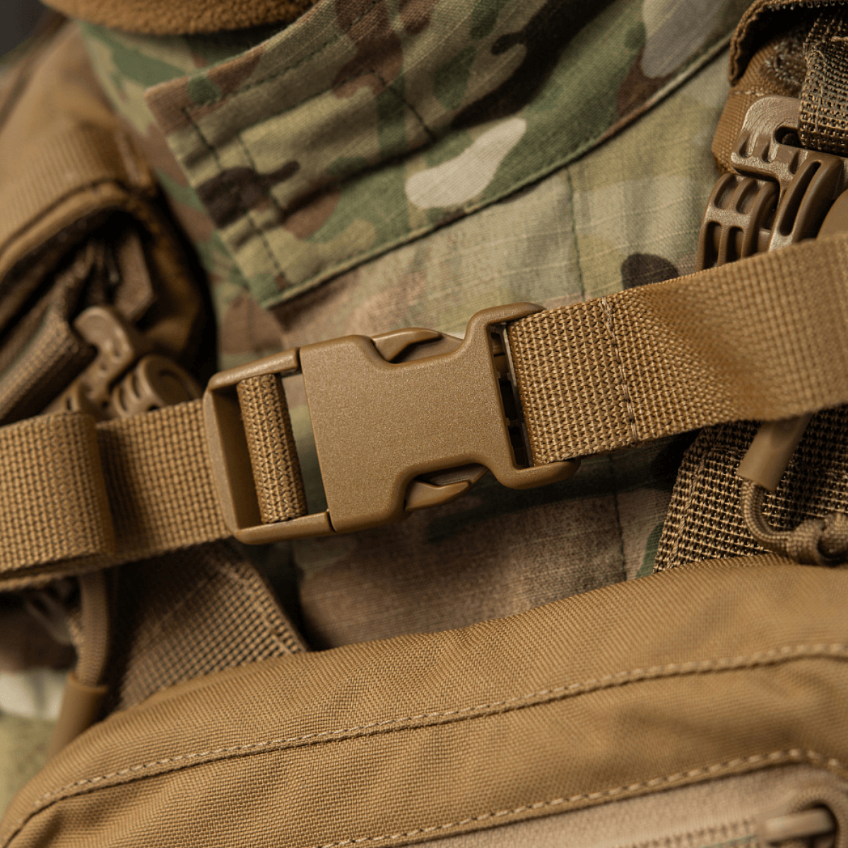 Nærbillede af M-Tac Rygsæk Sturm Elite Gen.II med robust spænde og camouflagebaggrund, ideel til taktiske aktiviteter.