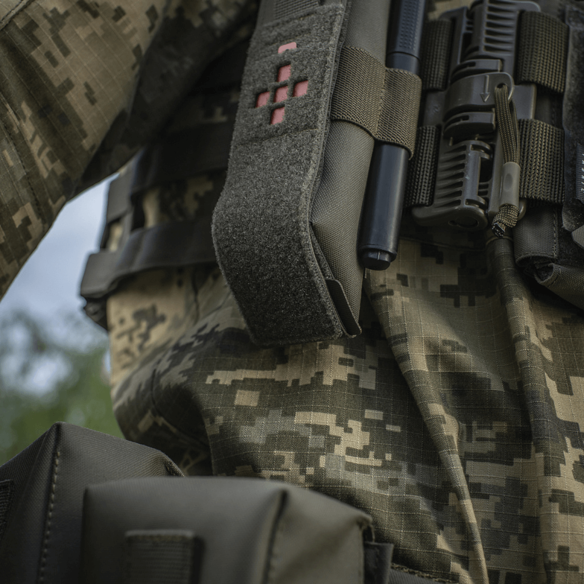 M-Tac Lomme til Tourniquet Closed fastgjort til militæruniform, designet til at beskytte og sikre tourniquet i nødsituationer.