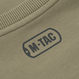 Nærbillede af M-Tac Pullover 4 Seasons logo på beige stof med ribbet kant.