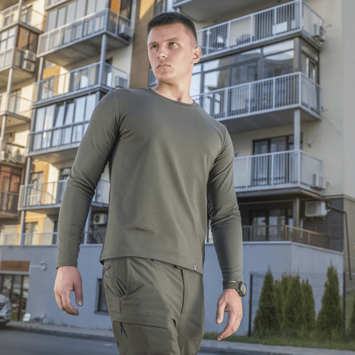 Mand iført M-Tac Long-sleeve T-shirt 93/7 foran moderne bygning