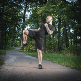 Mand i sort træningstøj udfører kampsport i skov ved sommeraften. M-Tac Shorts Casual Fit Cotton fremhævet. Komfort og stil.