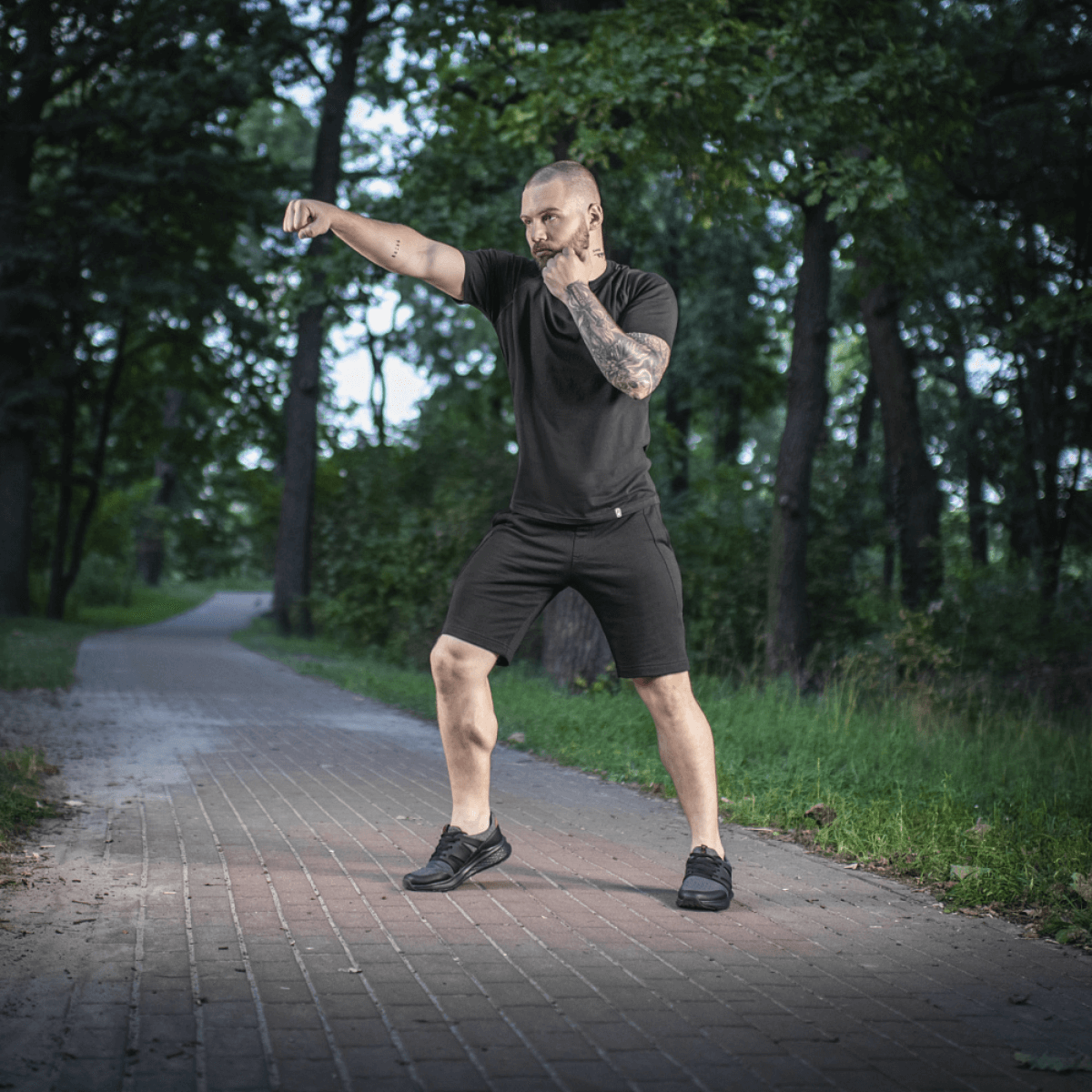 Mand i skoven iført M-Tac Shorts Casual Fit Cotton træner i sommervejr, viser stilrent design og høj komfort.