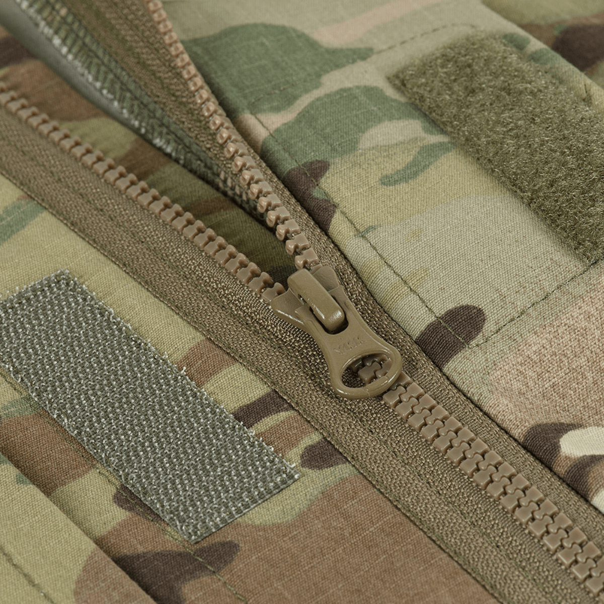 Nærbillede af lynlåsen på M-Tac Feltjakke NYCO i Multicam-mønster. Jakken har holdbart amerikansk NYCO-stof til slidstyrke og åndbarhed.