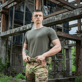 Mand iført M-Tac T-shirt 93/7 Summer foran en industriel baggrund.