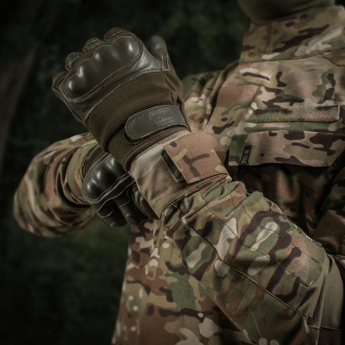 M-Tac Jakke Sturm NYCO Extreme i Multicam-mønster, militærjakke i slidstærkt nylon-bomuldsstof, vises i naturscene.