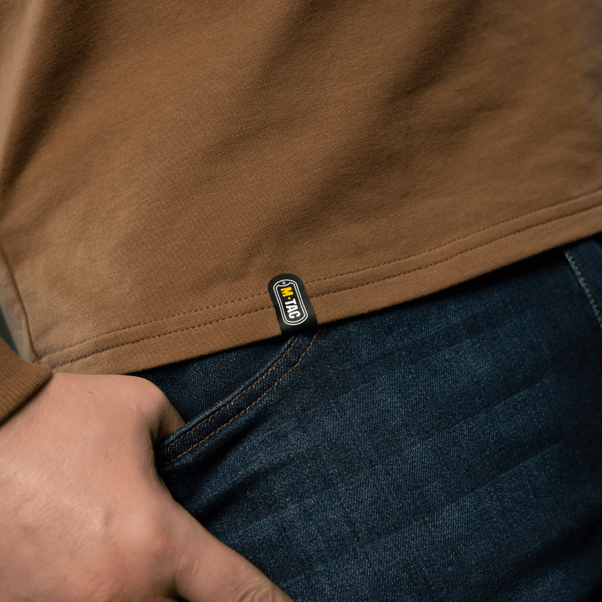 M-Tac Raglan Athlete sweatshirt i farven coyote, detaljeret visning af mærke og søm ved en lomme, ideel til daglig brug og sport.