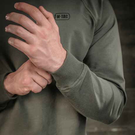 M-Tac Raglan Athlete sweatshirt med lange raglanærmer i oliven, vises med tæt udsnit af ærme og logo.