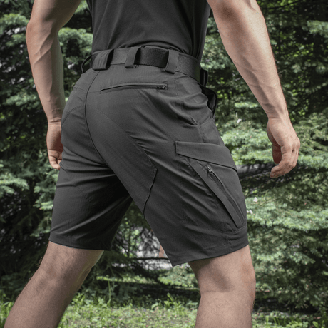 Mand iført M-Tac Aggressor Summer Flex Shorts udendørs, fremhæver de taktiske funktioner og lommedesign.