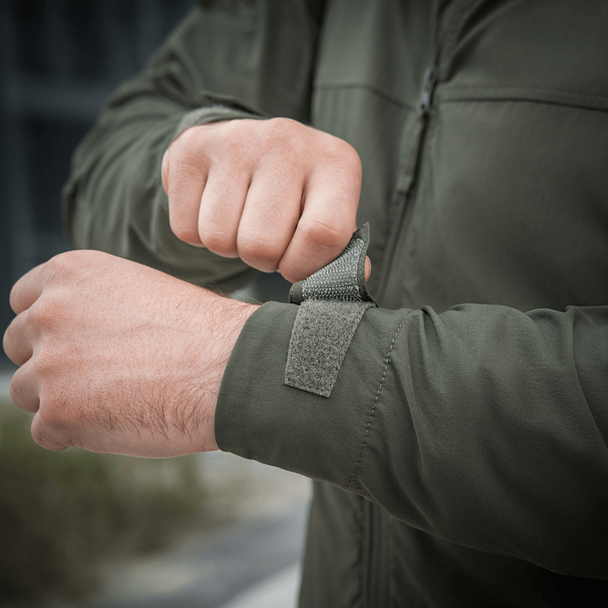 Person justerer ærme af M-Tac Flash Jakke, letvægtsjakke ideel til vandreture og hverdagsbrug, nem at kombinere med almindeligt tøj.