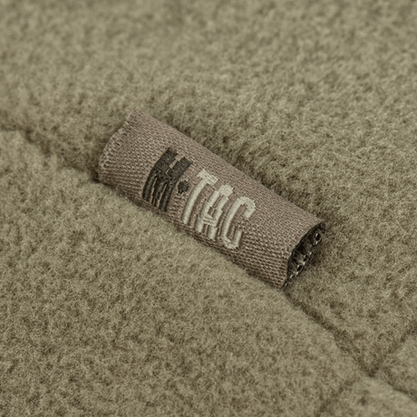 Nærbillede af M-Tac Combat Fleece Polartec Jakke i olivengrøn, viser detaljeret struktur og mærket på fleece materialet.