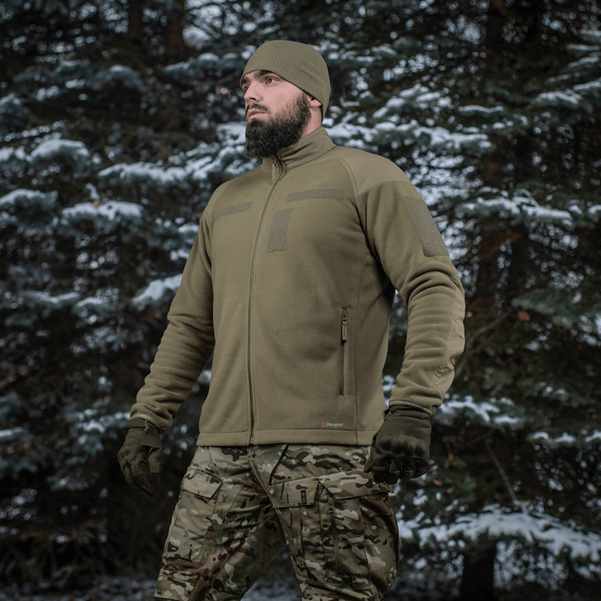 Mand iført M-Tac Combat Fleece Polartec Jakke i skovmiljø, viser jakkeens varme og funktionelle design.