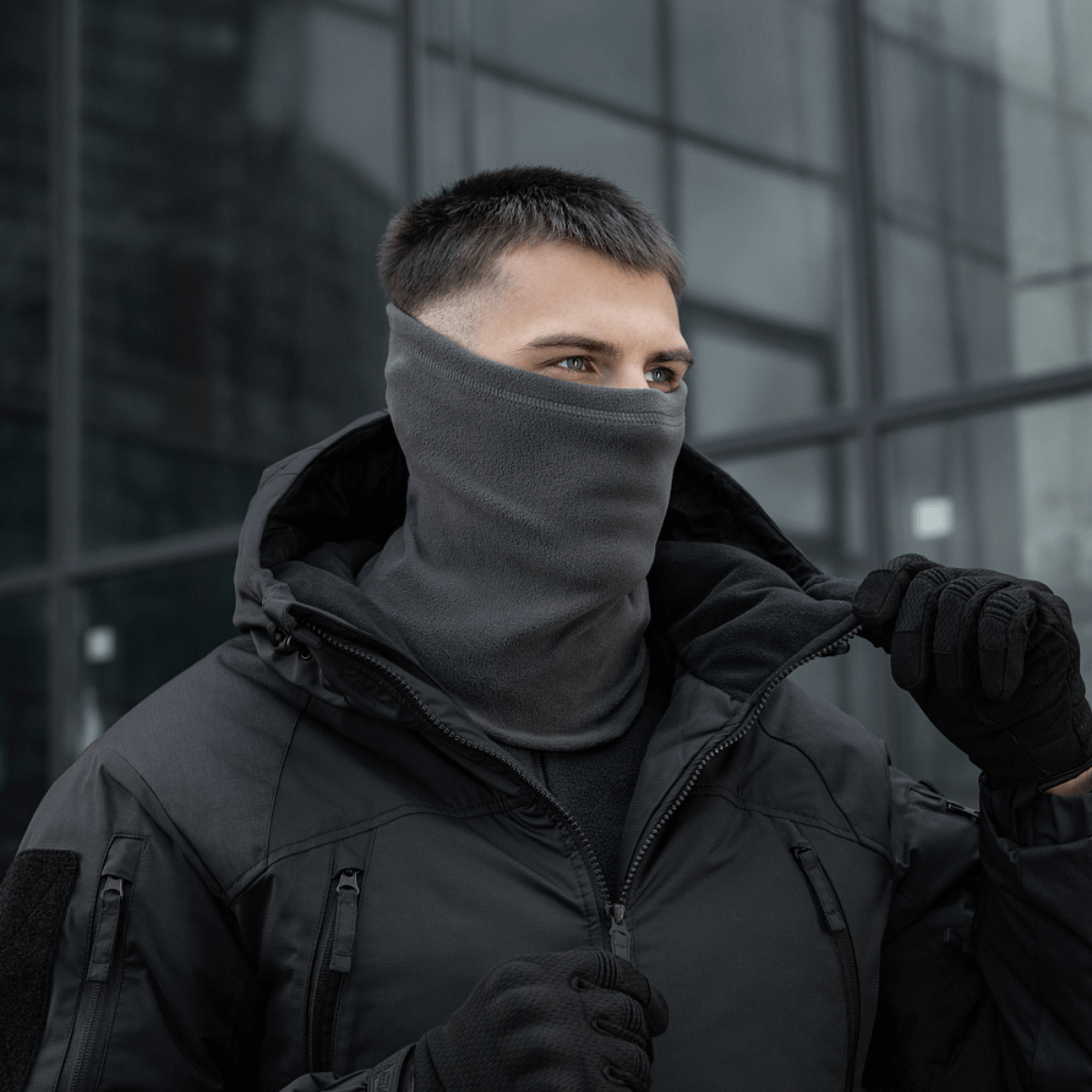 Mand iført M-Tac Polartec Lang Tubehalstørklæde i grå farve i koldt vejr, alsidig beskyttelse mod vind, perfekt til udendørsaktiviteter.