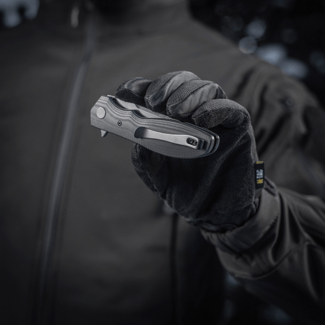 Person holding M-Tac Outdoor & Militær foldekniv - Type 6 with black G10 composite handle in gloved hand