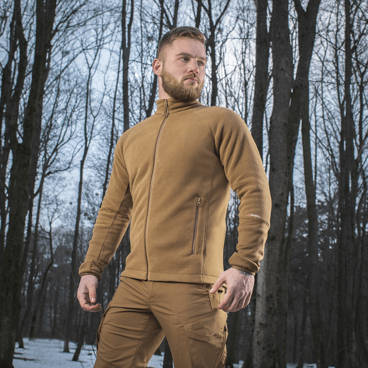 M-Tac Polartec Sport Fleecejakke i naturen, ideel til overgangsvejr, viser et stilrent og funktionelt design i skovmiljø.