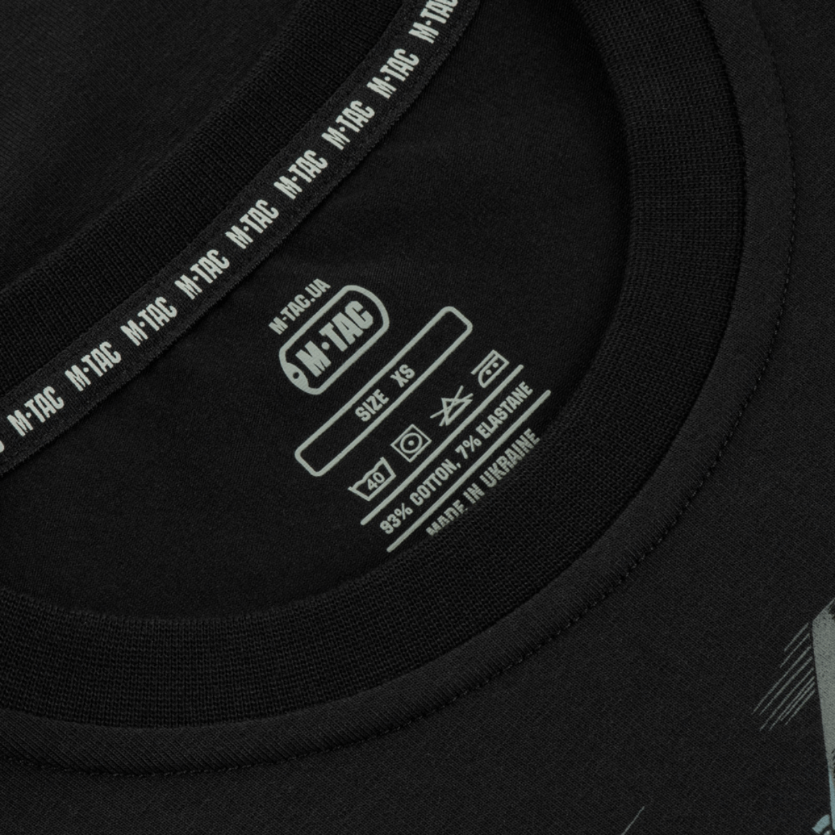 Nærbillede af M-Tac T-Shirt Surf Club mærke og størrelsesetiket, lavet i Ukraine med 93% bomuld og 7% elastan.