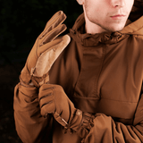 Mand iført brune M-Tac Handsker Scout Tactical med læderhåndflader, viser fleksibilitet og komfort til udendørsbrug.