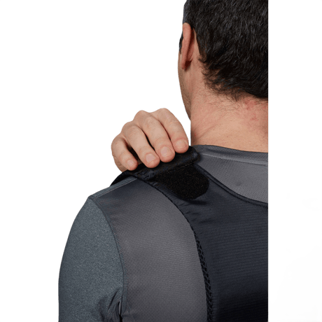 Mand iført Anorak Topaz® Concealable III Stiksikker Vest, justerer skulderstroppen for optimal skjult beskyttelse.