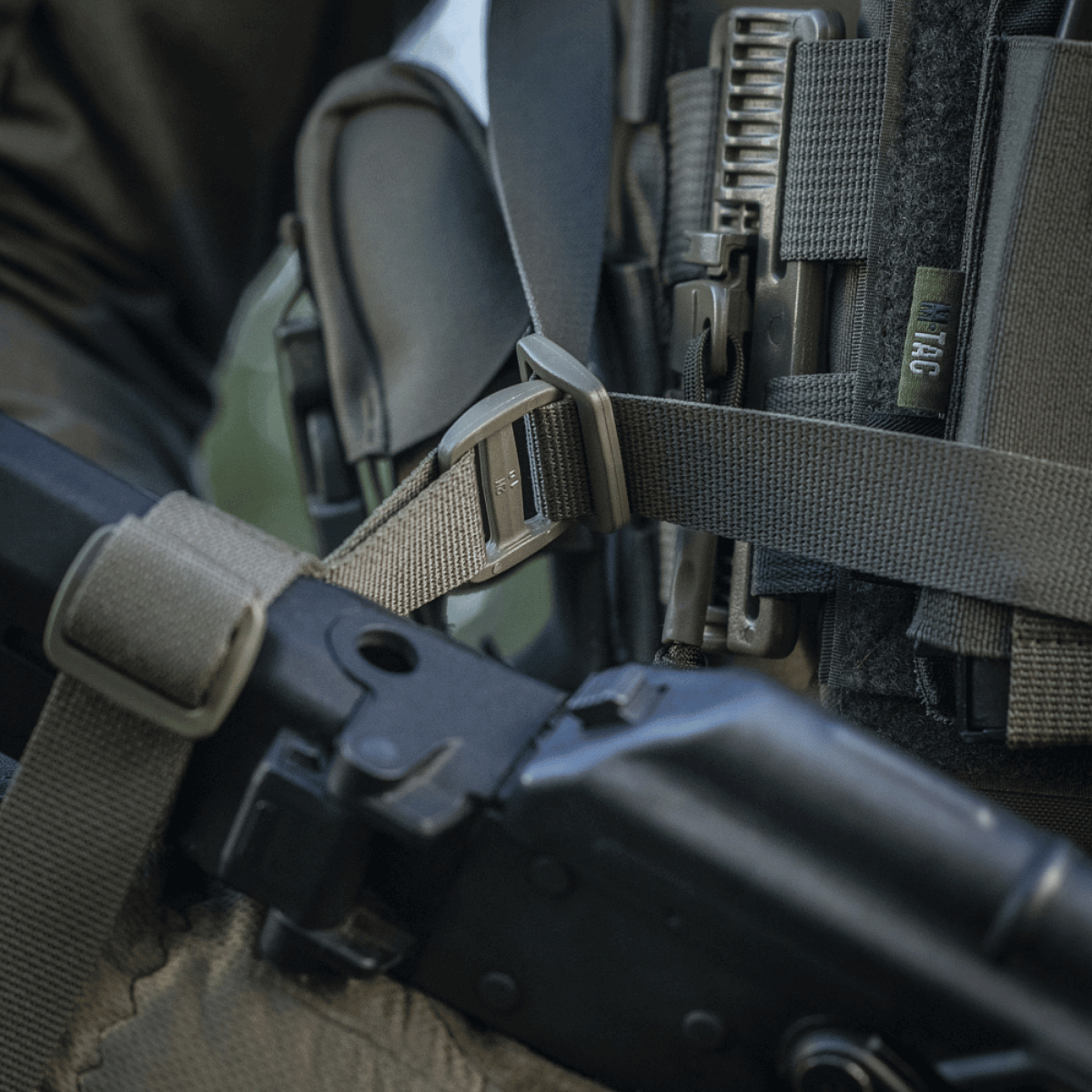 M-Tac Våbenbælte med Tre Punkter i brug til patruljering og konvojopgaver, designet til let våbenoverførsel mellem skuldre.