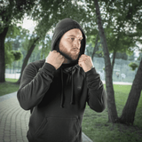 Mand iført M-Tac Hættetrøje Cotton Raglan i park, fremstillet i blødt bomuld med raglanærmer for optimal komfort og bevægelsesfrihed.