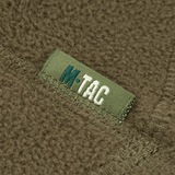 Nærbillede af M-Tac Anatomisk Snood Justerbar Elite Fleece (320 g/m²) med synlige stofdetaljer og logo på grøn baggrund.