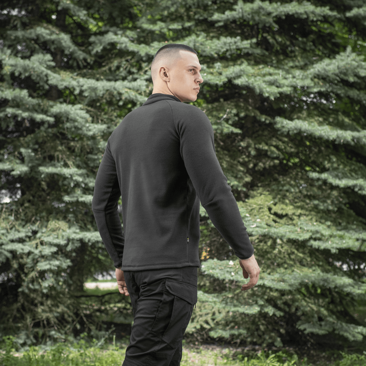 Mand iført M-Tac Delta Polartec Raglan Jakke, sort farve, med behagelig og varm fleece, ideel til udendørs brug.