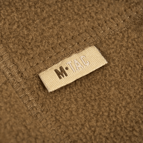 Et nærbillede af M-Tac Fleece Neck Gaiter med Snor, viser det bløde fleece-materiale og mærkelappen.
