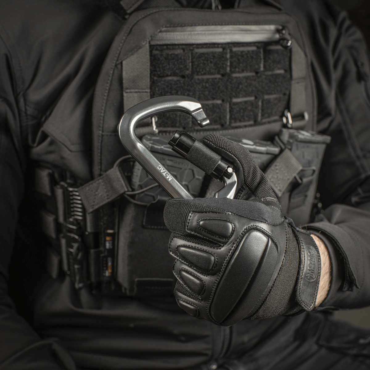 M-Tac Key-Lock Karabinhage af aluminium, egnet til klatring og sikkerhed, holdt af en person i taktisk udstyr.