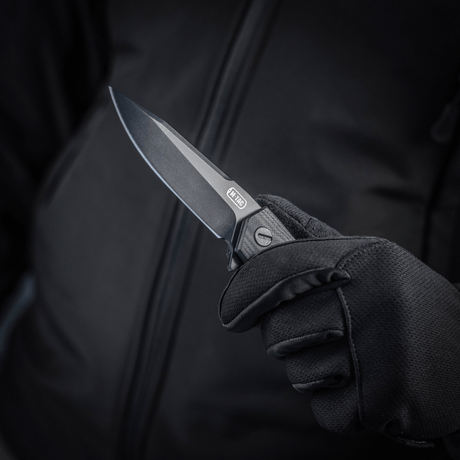 M-Tac Outdoor & Militær foldekniv - Type 6 holdt i en hånd iført sort handske, krom rustfrit stål klinge, G10-komposit håndtag.