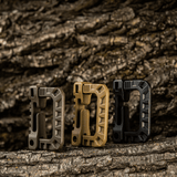 Tre M-Tac Plast Karabiner i forskellige farver på træbaggrund, lavet af holdbart ABS-plast, ideel til fastgørelse af udstyr.