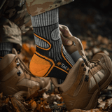 Person iført M-Tac Sokker Polar Merino 40% i kamuflagetøj og vandrestøvler, passende til udendørs aktiviteter og vandreture.