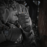 En person iført M-Tac Handsker Police Gen.2 med taktisk udstyr og hættejakke i en mørk udendørs setting.