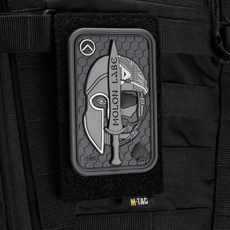 M-Tac Patch Molon Labe 3D PVC med spartansk design og velcro, fastgjort på taktisk taske. Gummi materiale med 3D-effekt. Dimensioner: 108x68 mm.