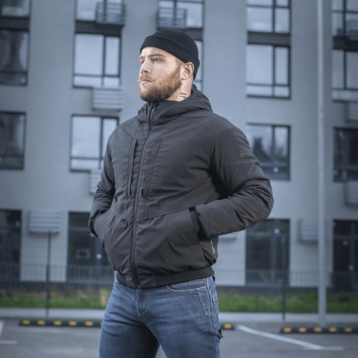 Mand bærer M-Tac Rubicon Jakke Gen. II – Slidstærk og varm bomberjakke foran moderne bygning