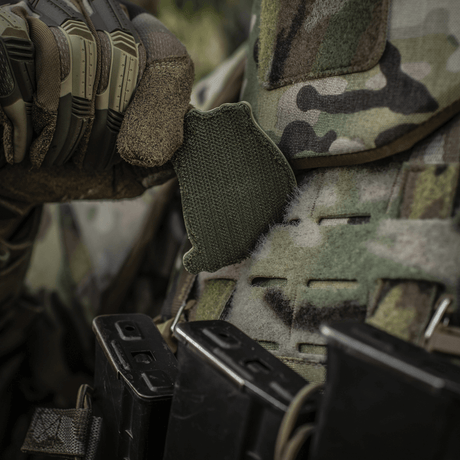 En soldat justerer en M-Tac Patch Jolly Roger PVC på sin camouflage-vest under taktisk træning udendørs.