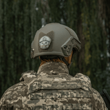 M-Tac Patch Emoji #4 med 3D-effekt monteret på en taktisk hjelm med camouflagebaggrund. Sjovt morale patch til udstyr.